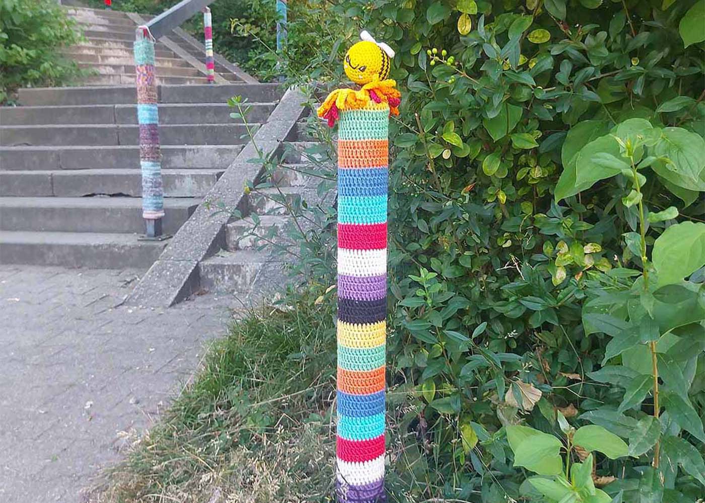 Ein Metallpfosten mit Guerilla-Häkelung im Sonnenhof